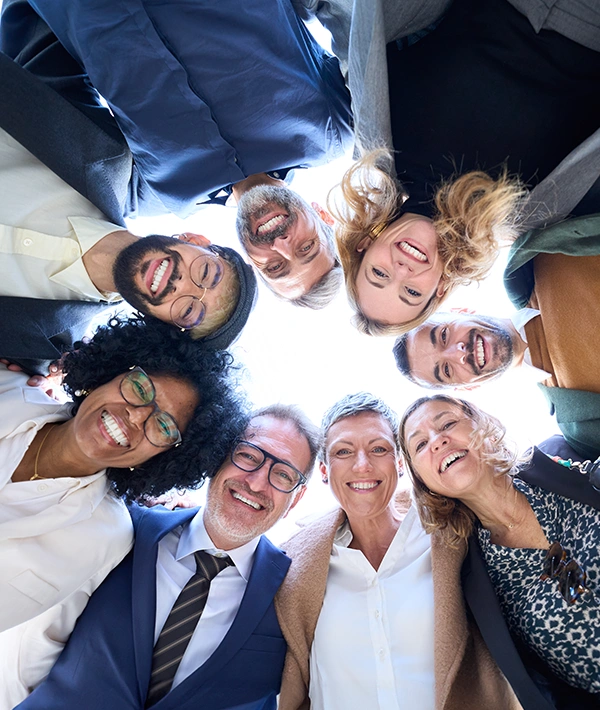 Diverse team of business professionals smiling together in a circle, representing organizational culture